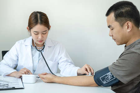 Doctor is checking blood pressure for the patient and using stethoscope to listening heartbeat while diagnosing disease and illness symptoms of patient at her clinicの写真素材