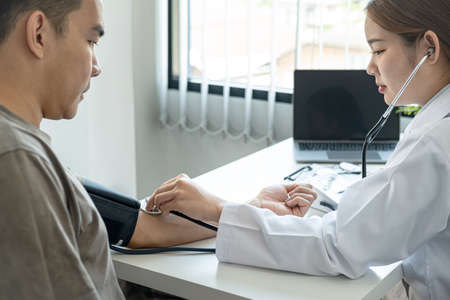 Doctor is checking blood pressure for the patient and using stethoscope to listening heartbeat while diagnosing disease and illness symptoms of patient at her clinicの写真素材