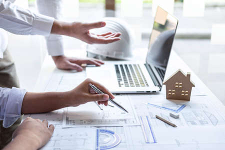 Construction engineering or architect discuss a blueprint while checking information on drawing and sketching meeting for architectural project in work site.の写真素材