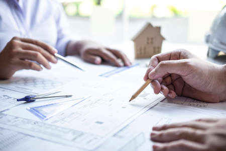 Team of construction engineering or architect partner discuss a blueprint while checking information on drawing and sketching meeting for architectural project with engineering equipment tool.の写真素材