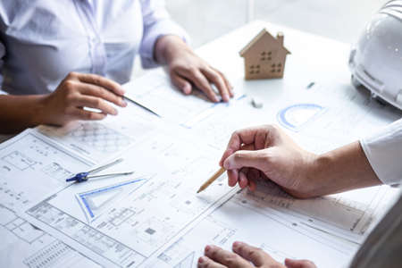 Construction engineering or architect discuss a blueprint while checking information on drawing and sketching meeting for architectural project in work site.の写真素材