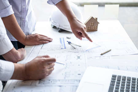 Team of engineering or architect meeting and discussing on blueprint and building model while checking information on sketching for architectural project.の写真素材