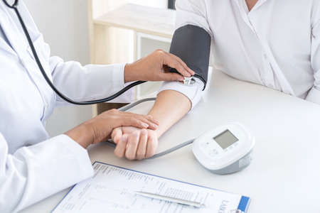 Doctor using a measuring blood pressure checking patient with examining, presenting results symptom and recommend treatment method, Healthcare and medical concept.の写真素材