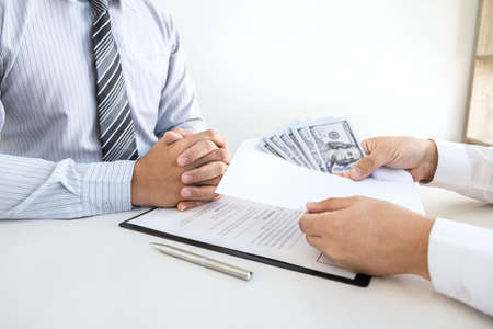 Dishonest cheating in business illegal money, Businessman giving bribe money in business people to accept agreement contract of investment deal, Bribery and corruption concept.の写真素材