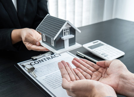 Estate agent giving house and keys to client after signing agreement contract real estate with approved mortgage application form for or house insurance.の写真素材