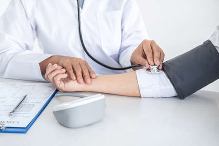Doctor using a measuring blood pressure checking patient with examining, presenting results symptom and recommend treatment method, Healthcare and medical concept.の写真素材