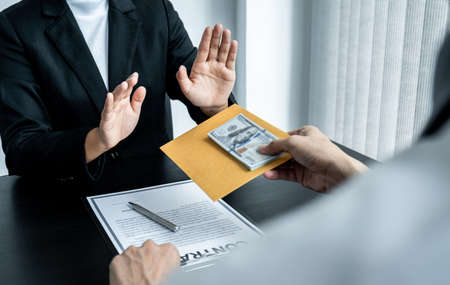 Business woman refusing and don't receive money banknote in envelope offer from business people to...