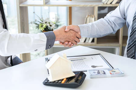 Finishing to successful deal of real estate, Broker and client shaking hands after signing contract approved application form, concerning mortgage loan offer for and house insurance.の写真素材