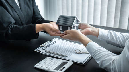 Estate agent giving house and keys to client after signing agreement contract real estate with approved mortgage application form for or house insurance.の写真素材