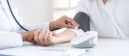 Doctor using a measuring blood pressure checking patient with examining, presenting results symptom and recommend treatment method, Healthcare and medical concept.の写真素材
