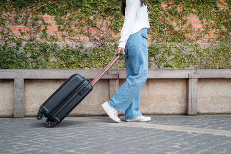 Asian woman tourist is going to holiday trip and walking to dragging with black luggage to passengers lounge in the airportの写真素材