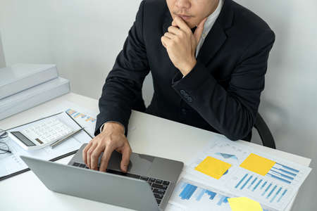 Businessman boss in suit is thinking and analysis of investments in new business from chart during...