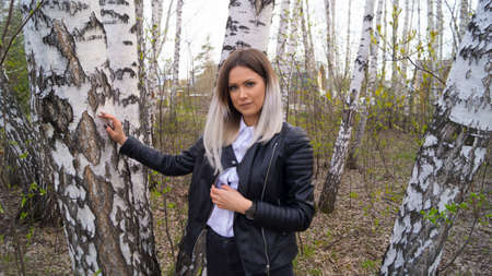 Beautiful young girl in a birch forest in the spring, the trees have just started to bloomの写真素材