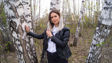 Beautiful young girl in a birch forest in the spring, the trees have just started to bloomの写真素材