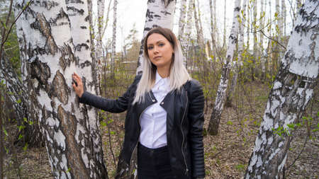 Beautiful young girl in a birch forest in the spring, the trees have just started to bloomの写真素材