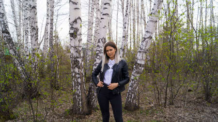 Beautiful young girl in a birch forest in the spring, the trees have just started to bloomの写真素材