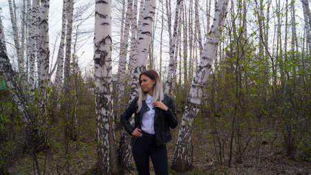 Beautiful young girl in a birch forest in the spring, the trees have just started to bloomの写真素材