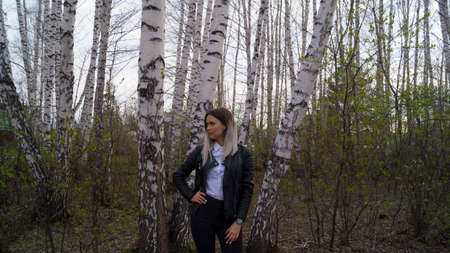 Beautiful young girl in a birch forest in the spring, the trees have just started to bloomの写真素材