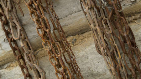 Old rusting chains hang on the wooden log wall of the houseの写真素材