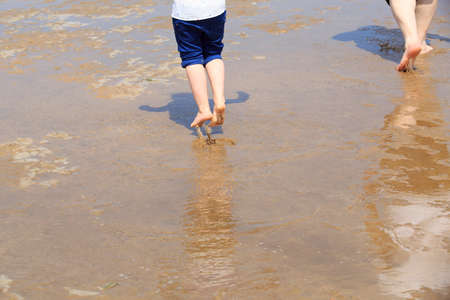 Bare feet jumping on a wet sandy beachの写真素材