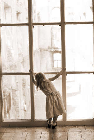Little girl looking out a large windowの写真素材