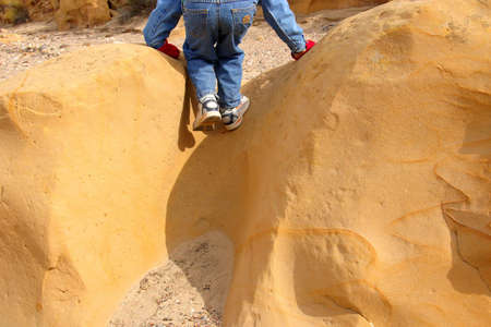 Child climbing sandstone rock in dry wash.の写真素材