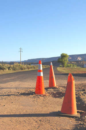 Three orange traffic cones near broken pavement.