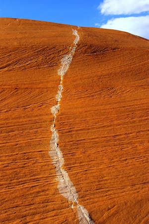 Steep red sandstone with stripe of white rock.の写真素材