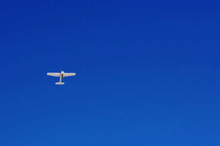 Small airplane flying alone in a clear blue sky.の写真素材