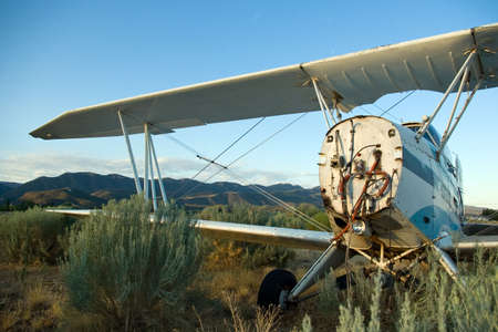 An old crop-dusting bi-plane abandoned in an overgrown field.の写真素材