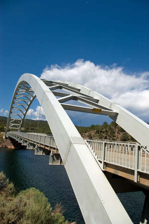 An arched highway bridge spanning a small lake with a storm in the sky.の写真素材