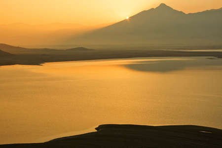 A bright yellow sun rises over a high desert lake.の写真素材