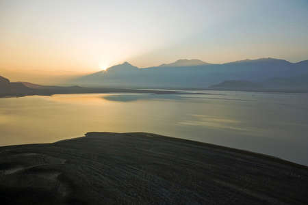 A cold autumn morning with the sun peaking over a distant mountain.の写真素材