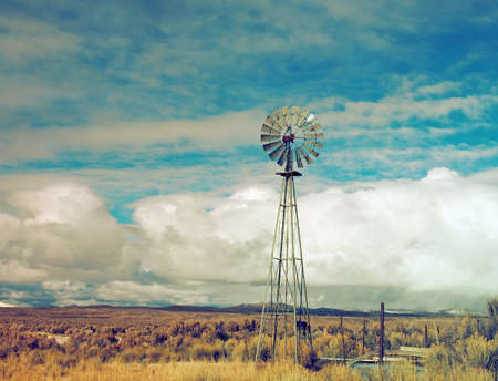 An old wind mill pumps water in ranch country.の写真素材