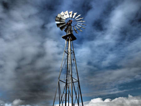 An old wind mill pumps water in ranch country.の写真素材