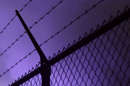 A dark iron fence, dark smoke in the backgroundの写真素材