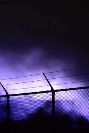 A black fence, threathening smoke in the backgroundの写真素材