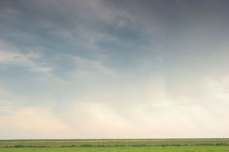 Green fields with mowed grass under a cloudy blue sky
