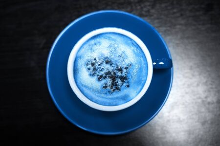 Toned classic blue photo. Coffee cup of cappuccino, top view.の写真素材