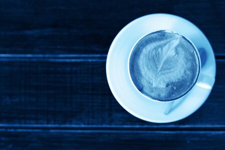Toned classic blue photo. Coffee cup of cappuccino, top view.の写真素材