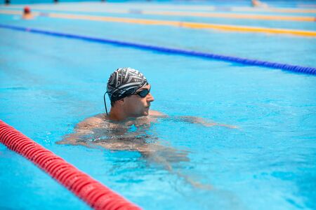 Healthy handsome athletic man enjoying summer vacation in swimming pool.