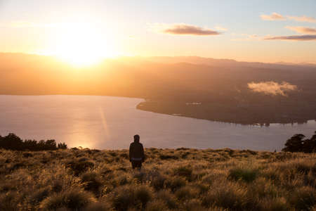 One person on top of mountain watching sunrise above lakeの写真素材
