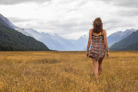 Girl walking through a field of grassの写真素材