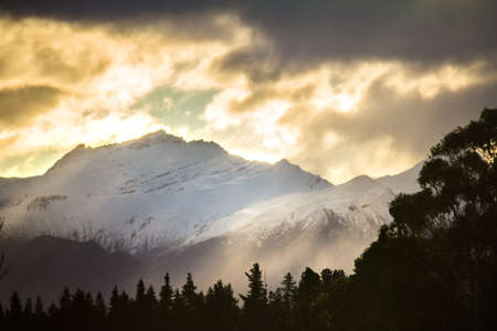 Snow capped mountains and sun beamsの写真素材