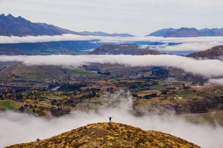 on top of the world man standing on mountain with view of clouds and riversの写真素材
