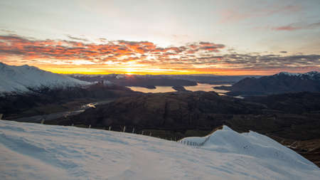 Sunrise above mountains and lake in the snowの写真素材