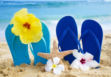 Flip flops and starfish with tropical flowers on sandy beach in Hawaiiの写真素材