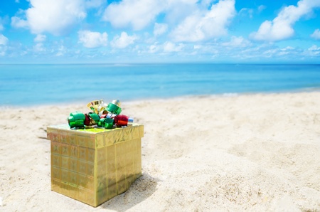Gold Gift box on sandy beach in sunny day- holiday conceptの写真素材