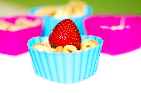 Few little cooking forms with cereals and one - with cereals and strawberry, on white table....