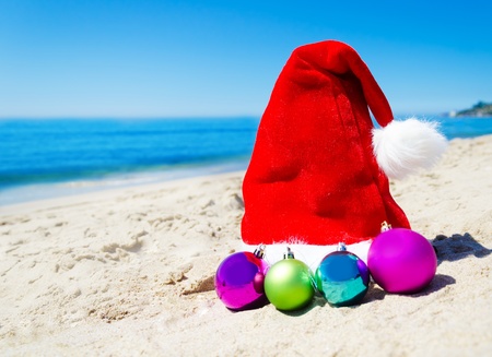 Christmas hat with christmas balls on the beach by the ocean - holiday conceptの写真素材